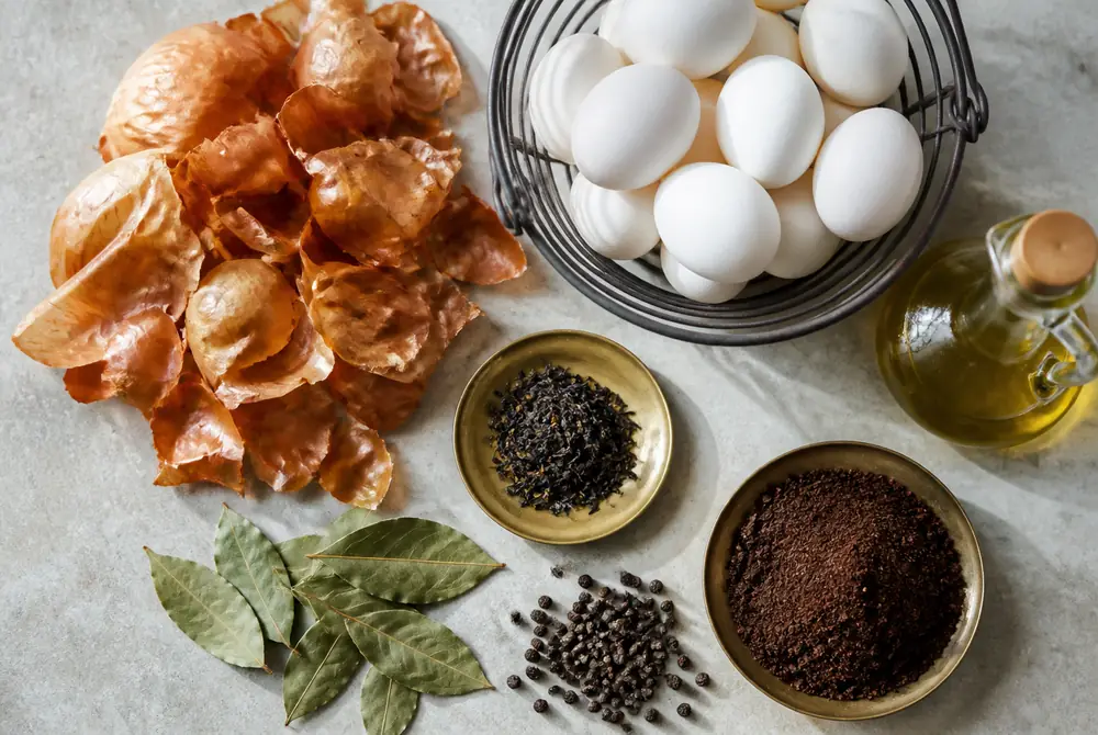 Ingredients for huevos haminados: white eggs, brown onion skins, black tea leaves, coffee grounds, bay leaves, peppercorns and olive oil
